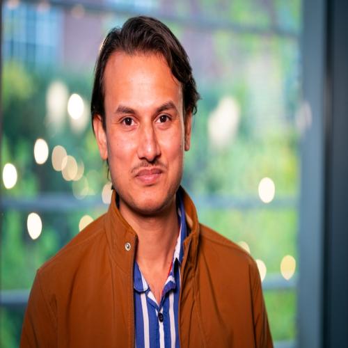 Man in brown jacket and blue and white striped shirt