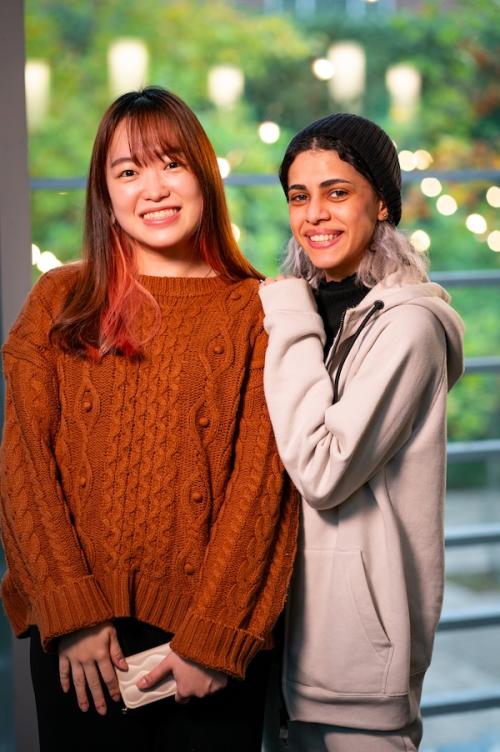 Two women smiling. Women on left hand side wearing brown sweater and women on right wearing beige hoodies