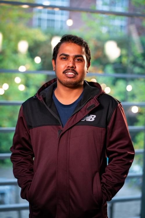 Man in burgundy jacket and navy blue shirt smiling